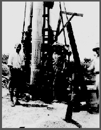 Miller (from left; first name unknown), Harry Burleigh and A.L. Lugn lower the screen and casing into the hole drilled by the Dempster rig, 1931.