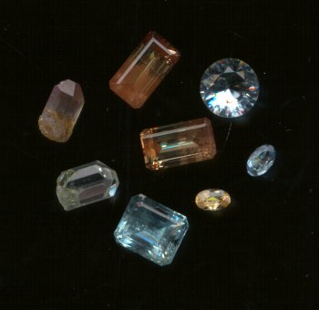 Faceted topaz and topaz crystals (crystals are two on the left side). These are probably from Brazil. 
