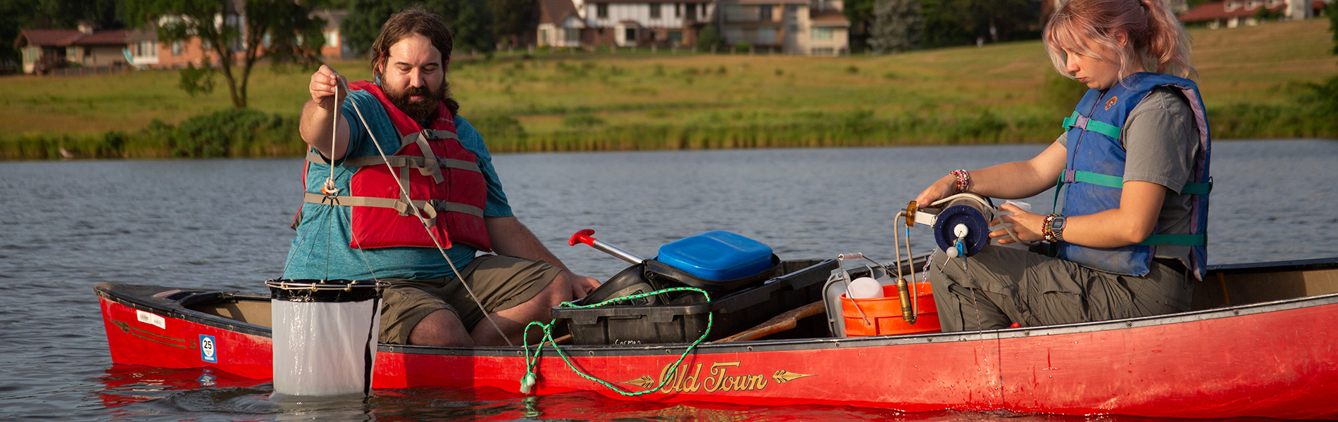 Two students in canoe with net in water
